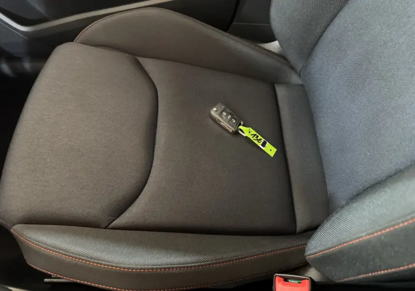 Gros plan sur le siège avant droit noir avec surpiqûres rouges et clé de contact SEAT Ibiza 2024 posée dessus.