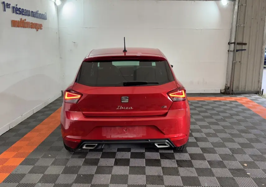 Vue arrière d'une SEAT Ibiza 1.0 TSI 110 FR rouge avec feux LED triangulaires et double sortie d'échappement chromée.