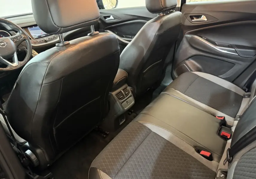 Vue intérieure arrière côté droit du Opel Grandland X 2021 avec sièges en cuir et tissu noirs et console centrale avec aérateurs.