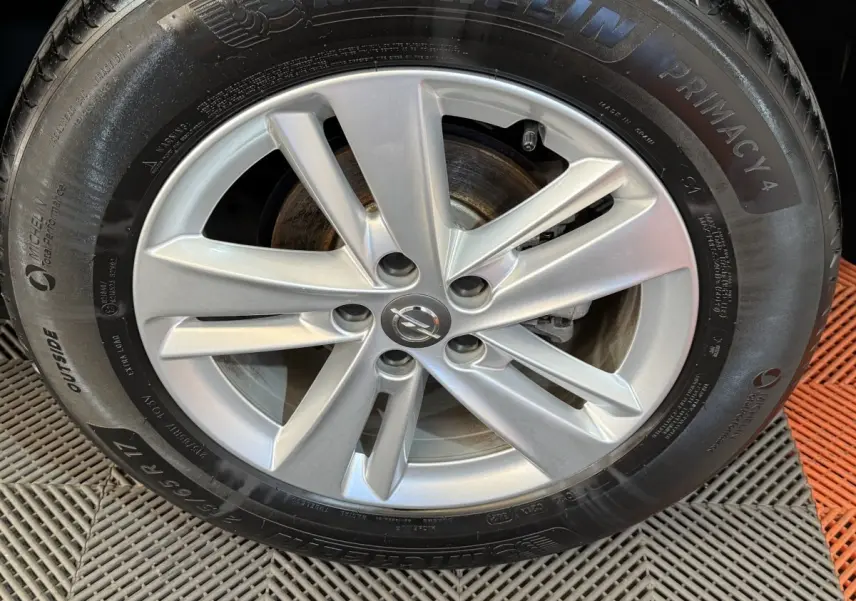 Gros plan sur la jante argentée et le pneu Michelin d’un Opel Grandland X noir, vue de face.
