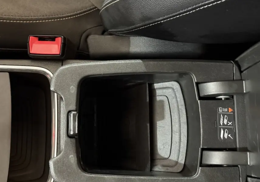 Vue plongeante sur le rangement central ouvert de l’Opel Grandland X noir, avec siège en cuir et ceinture rouge visible.