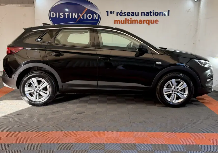 Opel Grandland X noir vue de profil côté gauche, avec jantes alliage et logo Distinxion en arrière-plan.