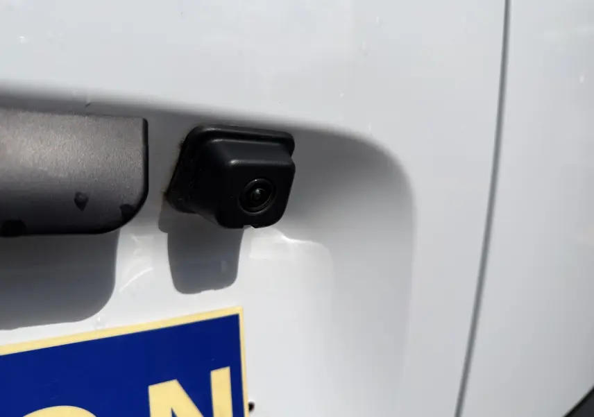 Gros plan sur la caméra de recul noire intégrée à la porte arrière blanche du Citroën Berlingo 2025.