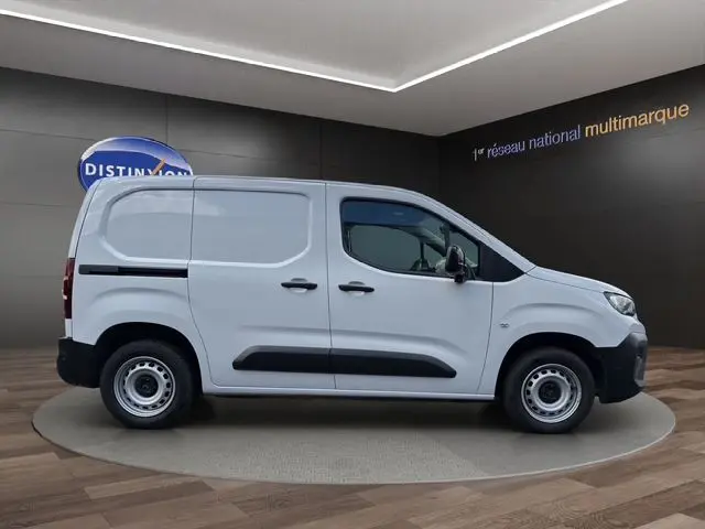 Vue latérale droite d’un Citroën Berlingo blanc version utilitaire avec protections noires et jantes acier en showroom.