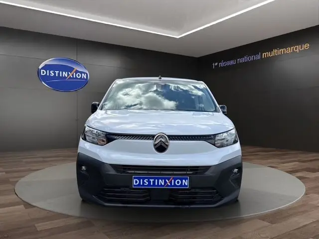 Vue frontale d'un Citroën Berlingo blanc 2025 avec logo distinctif et plaque Distinxion en showroom.