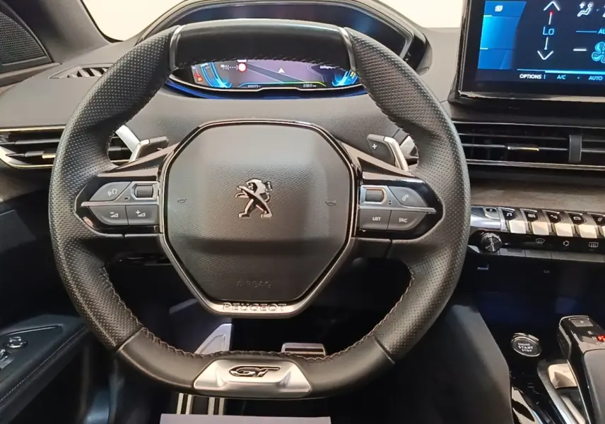 Vue rapprochée du volant cuir noir GT de la Peugeot 3008 hybride avec tableau de bord digital et console tactile.