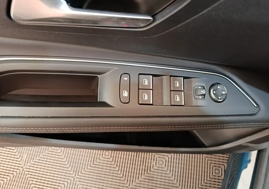 Vue rapprochée de la commande des vitres et rétroviseurs sur la porte côté conducteur d’un Peugeot 3008 bleu.