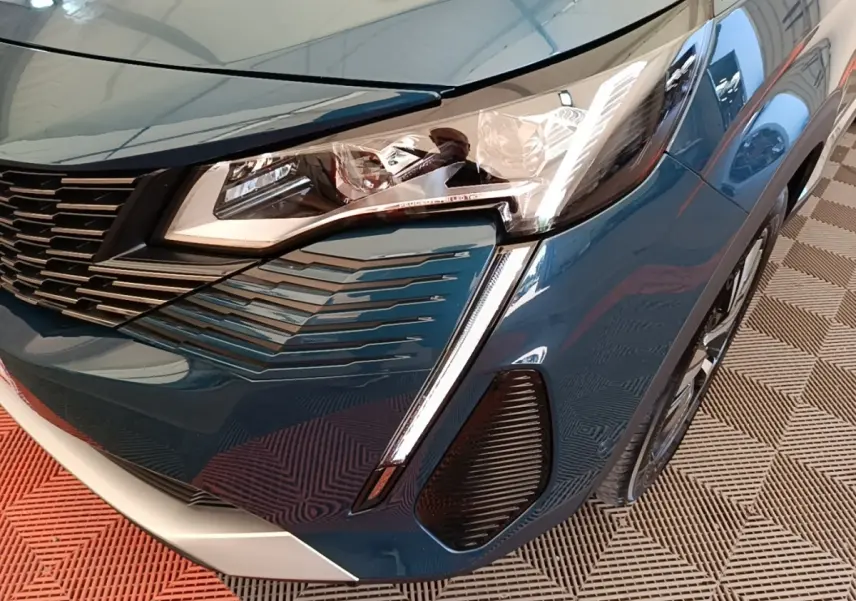 Gros plan sur l’avant droit bleu du Peugeot 3008 1.6 Hybrid 225 GT avec phares LED et calandre distinctive.