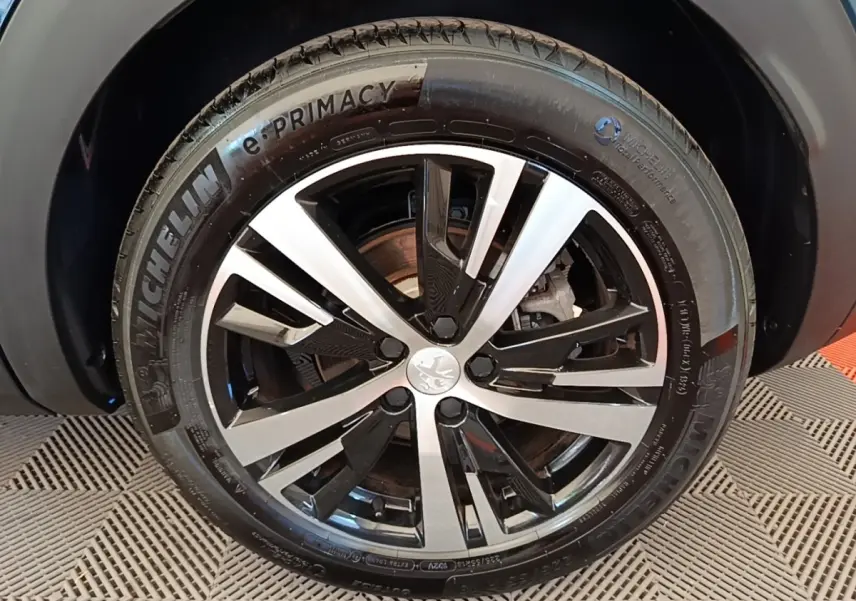 Gros plan sur la jante alliage bicolore et pneu Michelin e-Primacy du Peugeot 3008 bleu hybride rechargeable.