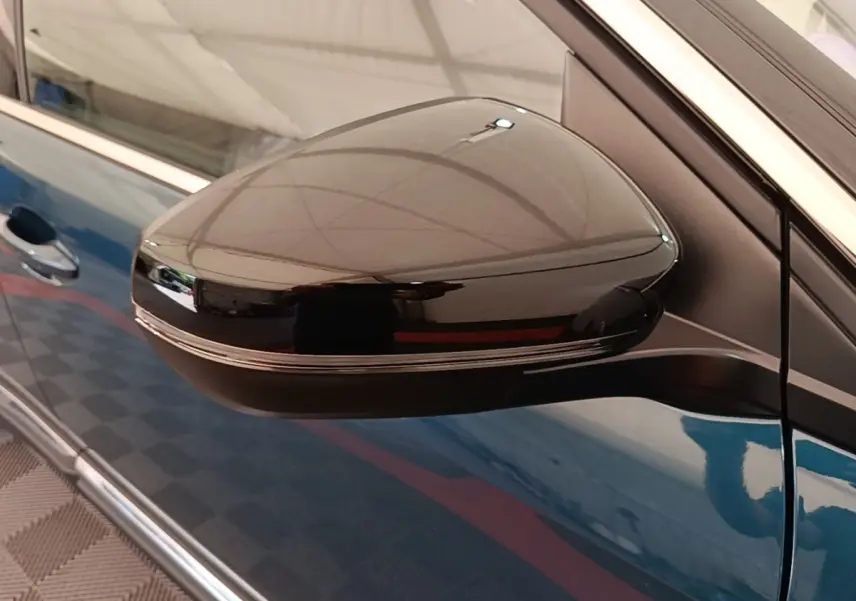 Rétroviseur latéral droit noir brillant sur Peugeot 3008 bleu, vue rapprochée côté porte avant.