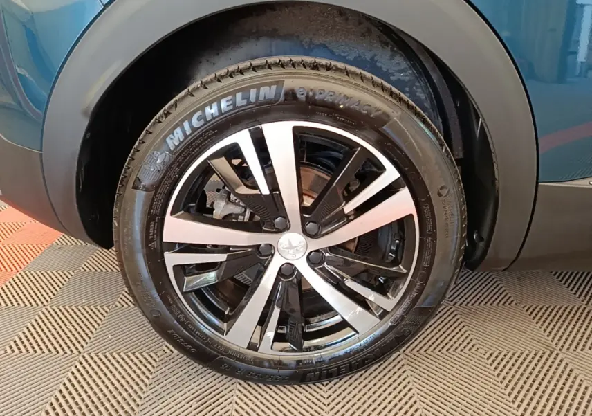 Gros plan sur la roue avant droite du Peugeot 3008 bleu, avec jante alliage bicolore et pneu Michelin.