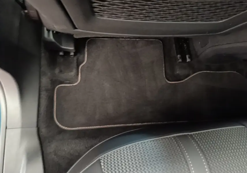 Vue rapprochée du tapis de sol noir et de la partie inférieure du siège arrière dans un Peugeot 3008 bleu hybride rechargeable.
