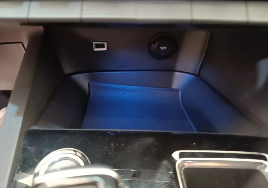 Gros plan sur la console centrale noire du Peugeot 3008 hybride, avec prise USB et prise 12V visibles.