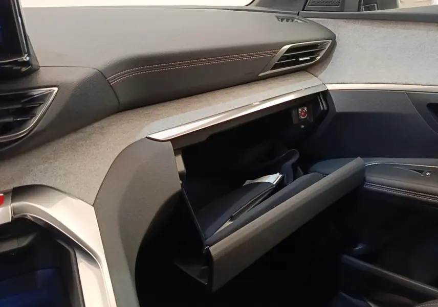 Intérieur côté passager du Peugeot 3008 Hybrid 2022, tableau de bord gris et noir avec boîte à gants ouverte.