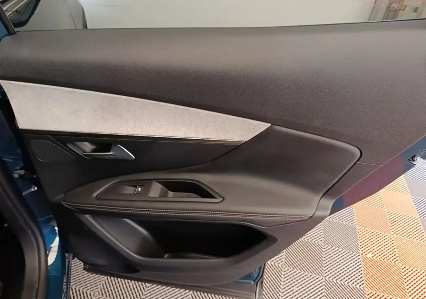 Vue intérieure de la porte avant gauche du Peugeot 3008 bleu, avec garniture noire et insert gris clair.
