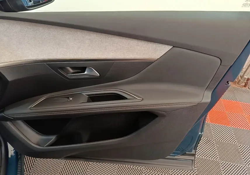 Vue intérieure de la porte avant gauche du Peugeot 3008 bleu, avec panneau en tissu clair et garniture noire.