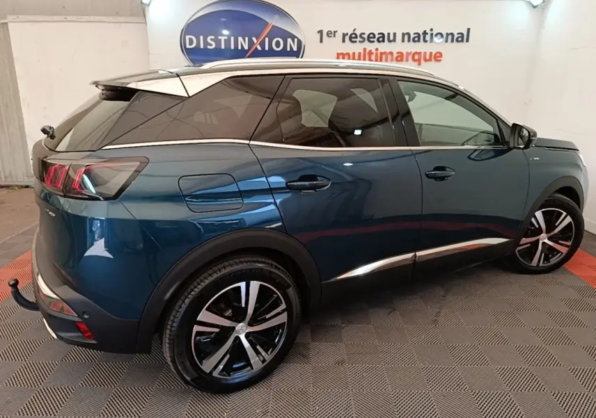 Vue 3/4 arrière droite du Peugeot 3008 hybride rechargeable bleu avec jantes alliage et toit blanc en intérieur showroom.