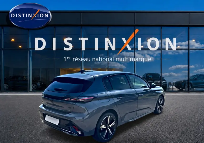Peugeot 308 1.2 hybrid 145 GT gris en 3/4 arrière droit devant une vitrine Distinxion.