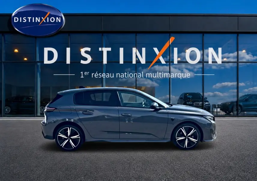 Profil côté gauche d'une Peugeot 308 gris métallisé 2025, avec jantes alliage et vitres teintées, devant une vitrine Distinxion.