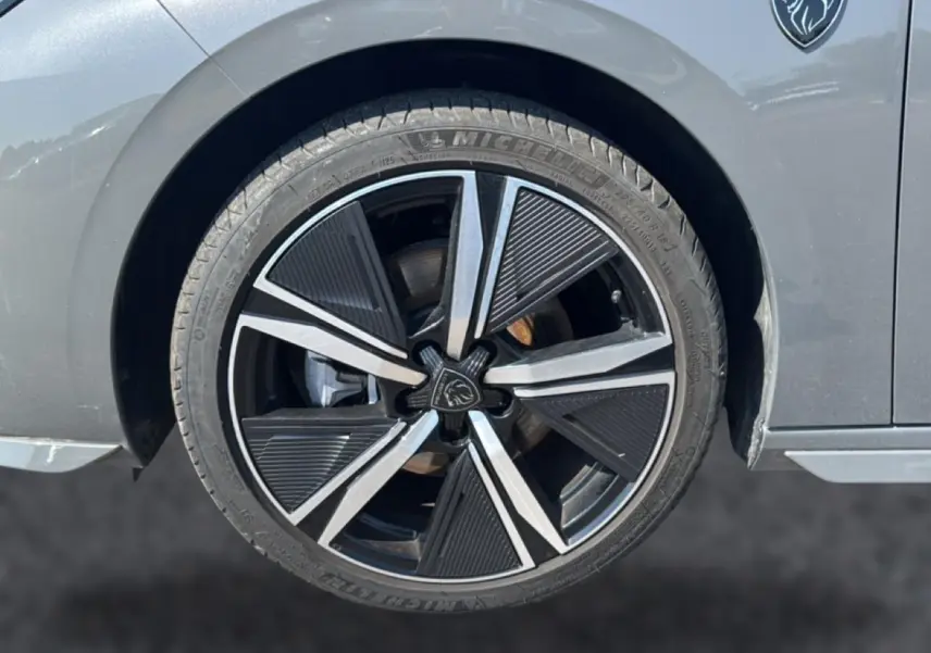 Gros plan sur la roue avant droite grise d'une Peugeot 308 1.2 hybrid 145 GT avec jante alu noire et argentée au design moderne.
