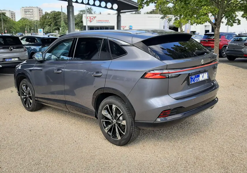 Vue 3/4 arrière droite d'un MG MOTOR EHS 1.5 HYBRID+ 224CH Luxury gris Camden avec jantes noires bicolores.