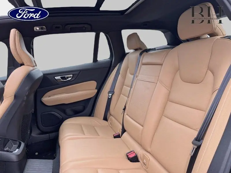 Vue intérieure arrière montrant les sièges en cuir brun d'une Volvo V60 T8 hybride rechargeable avec toit panoramique.