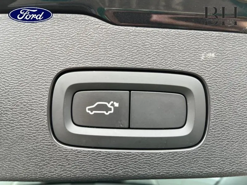 Bouton de déverrouillage du coffre sur tableau de bord en cuir brun d'une Volvo V60 T8 gris Savile.