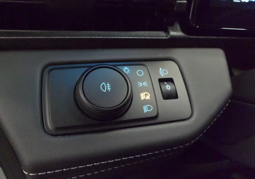 Gros plan sur la commande d'éclairage intérieure du Ford Puma 2025 gris Cactus, avec molette et réglage de phares.