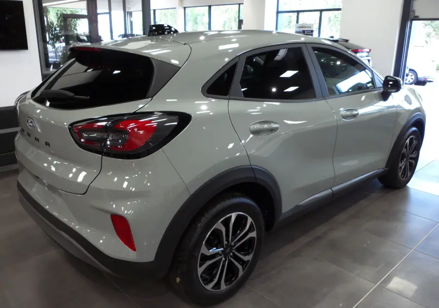 Ford Puma gris Cactus vu de trois quarts arrière droit avec jantes biton et feux arrière LED dans un showroom.