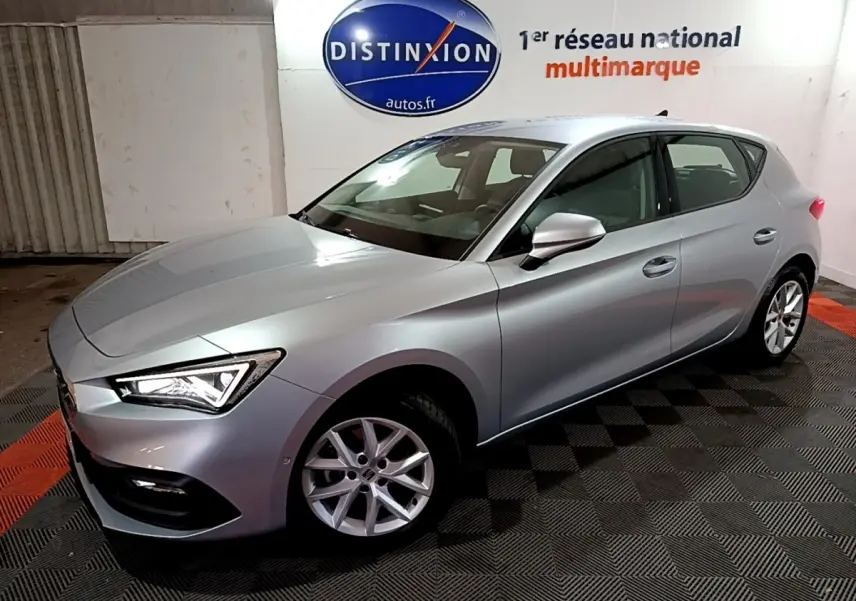 SEAT LEON gris clair vue 3/4 avant droit en intérieur avec jantes alliage et phares LED allumés
