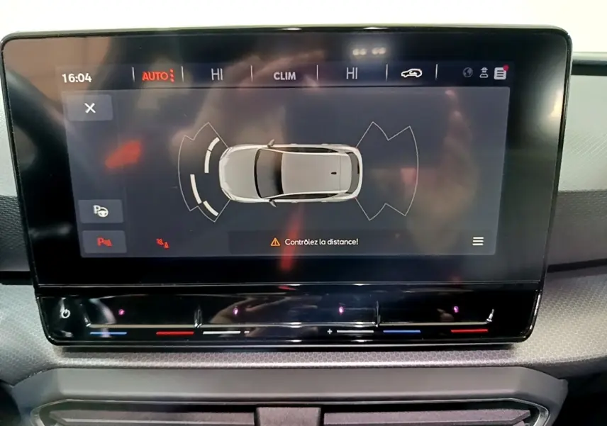 Écran tactile central affichant l'aide au stationnement avec vue aérienne du véhicule gris clair SEAT Leon 2023.