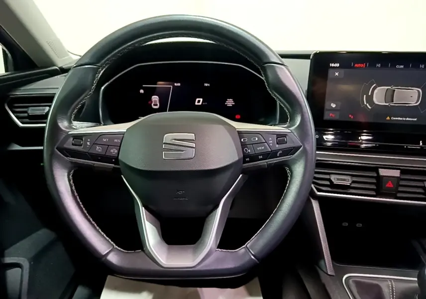 Vue intérieure centrée sur le volant cuir noir du SEAT Leon 2023 avec tableau de bord digital et écran tactile.