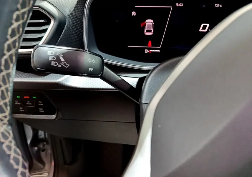Détail du tableau de bord et levier de clignotants dans l'habitacle gris clair d'une SEAT Leon 2023.