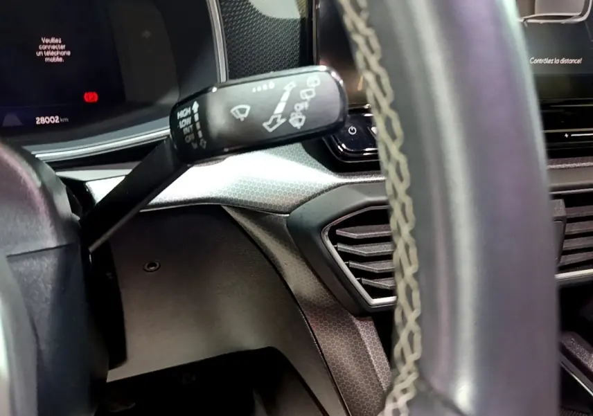 Gros plan sur la manette d’essuie-glace à gauche du volant en cuir avec surpiqûres dans l’habitacle gris du SEAT Leon.