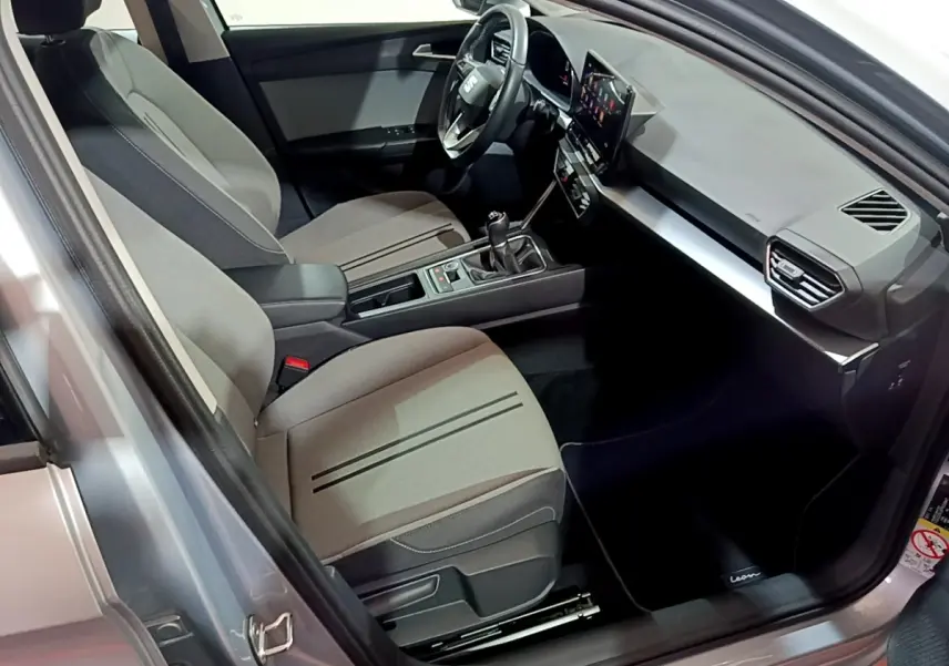 Intérieur côté conducteur du SEAT Leon gris clair 2023, avec tableau de bord moderne et écran tactile central.