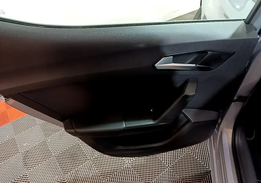 Vue rapprochée de la porte côté gauche gris clair d'une SEAT LEON 2023 avec poignée argentée et garniture noire.