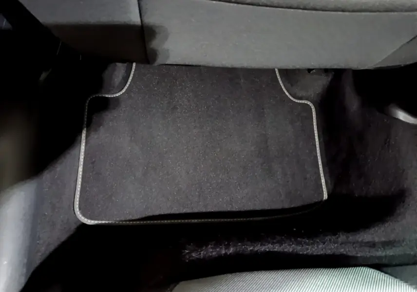 Tapis de sol noir avec surpiqûres blanches sous le siège arrière d'une SEAT Leon gris clair 2023