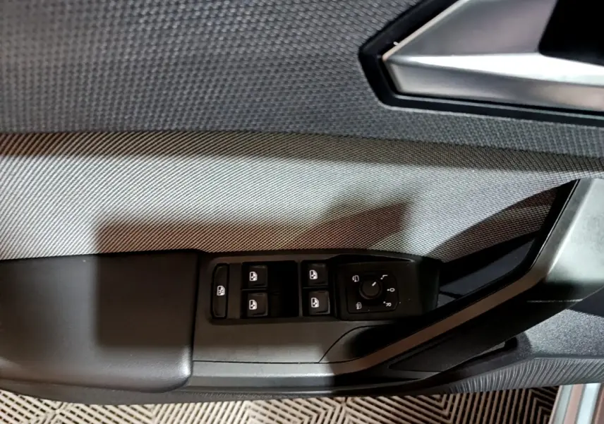 Gros plan sur la commande des vitres et rétroviseurs côté conducteur d'une SEAT Leon gris clair 2023.