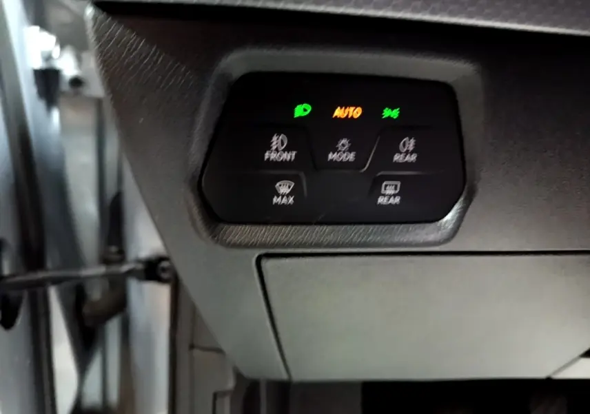 Panneau de commandes d'éclairage avec voyants verts et orange dans l'habitacle d'une SEAT Leon gris clair.