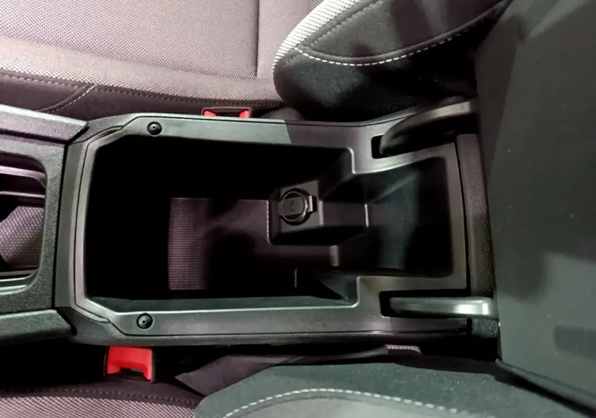 Vue plongeante sur le rangement central noir entre les sièges avant du SEAT Leon gris clair 2023.