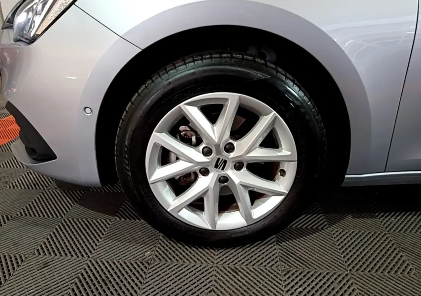 Gros plan sur la roue avant gauche gris clair d'une SEAT LEON 2023 avec jante alliage à 5 branches doubles.