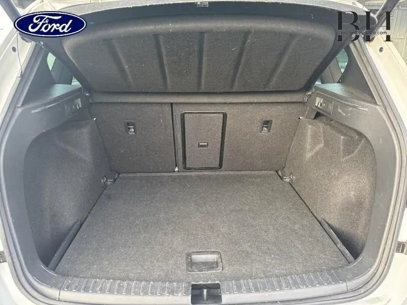 Coffre ouvert vu de l'arrière d'un SEAT Ateca blanc Nevada Métal, espace de chargement vide et tapis gris foncé.