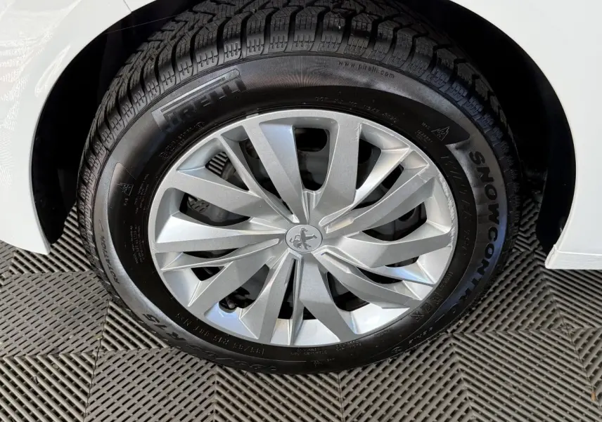 Gros plan sur la roue avant droite argentée d'une Peugeot 208 PureTech 75 S&S Like blanche, pneu hiver Pirelli.