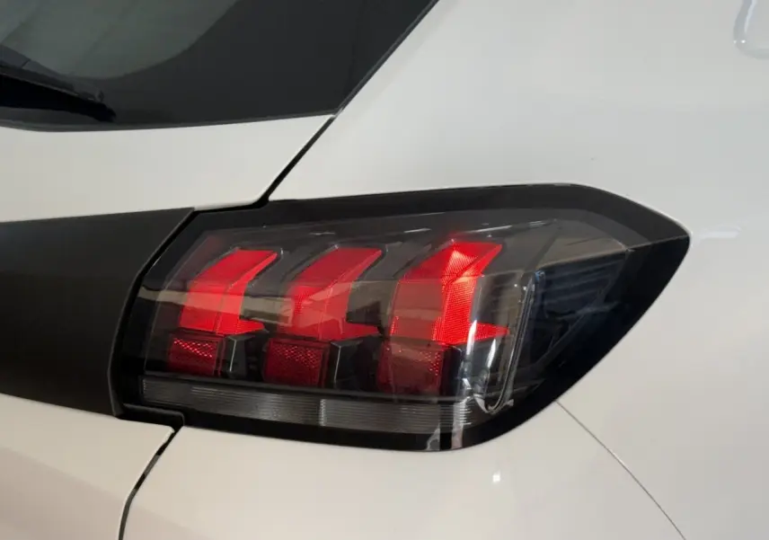 Gros plan sur le feu arrière droit noir et rouge d’une Peugeot 208 PureTech 75 S&S Like blanche.