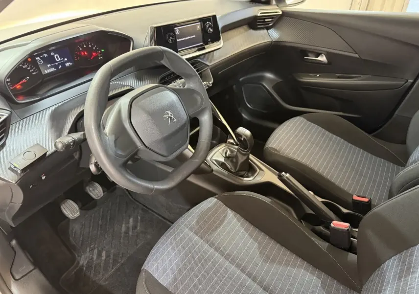 Vue intérieure côté conducteur de la Peugeot 208 PureTech 75 S&S Like 2020 avec sièges gris et volant compact noir.