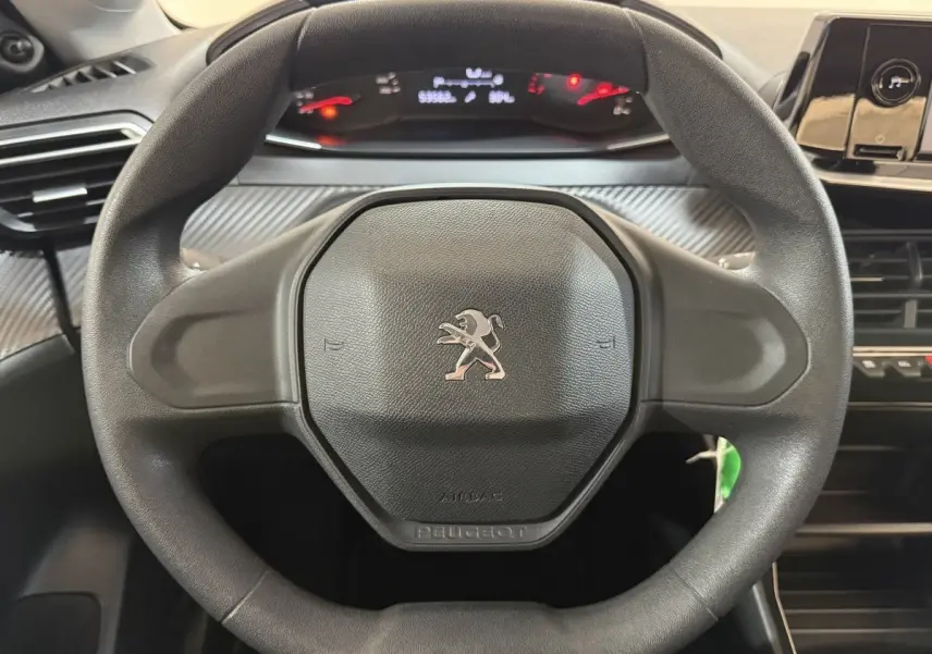 Vue rapprochée du volant noir de la Peugeot 208 PureTech 75 S&S Like avec tableau de bord et commandes visibles.