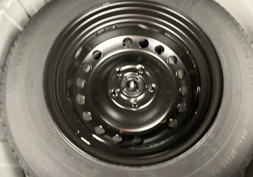 Gros plan sur la roue de secours noire du Renault Captur TCE 140 EDC 21 Business, visible en intérieur coffre.