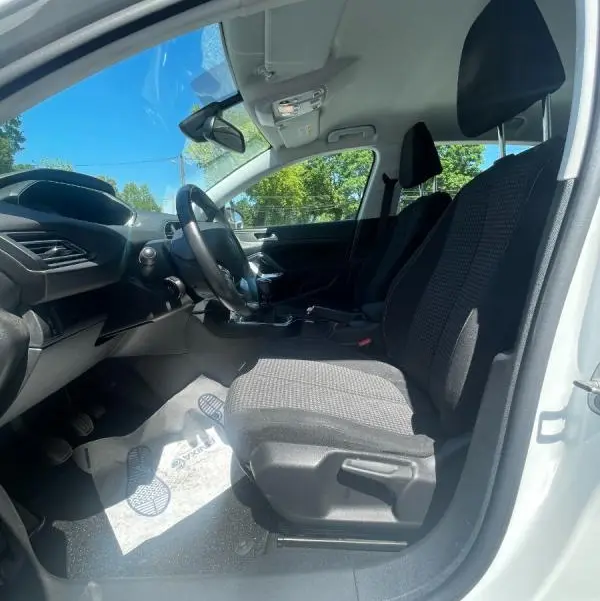Vue intérieure côté conducteur de la Peugeot 308 blanche 2020, montrant les sièges avant et le tableau de bord.