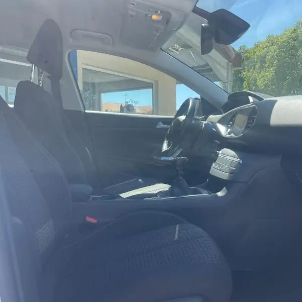 Vue intérieure côté conducteur de la Peugeot 308 blanche de 2020, montrant les sièges et la console centrale.
