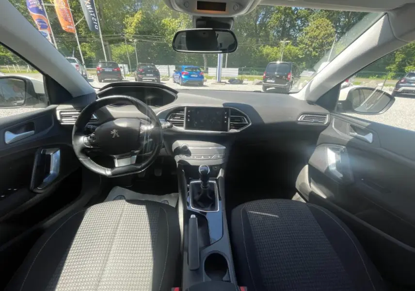 Vue intérieure avant du Peugeot 308 blanc 2020, montrant le volant, tableau de bord et levier de vitesse manuel.